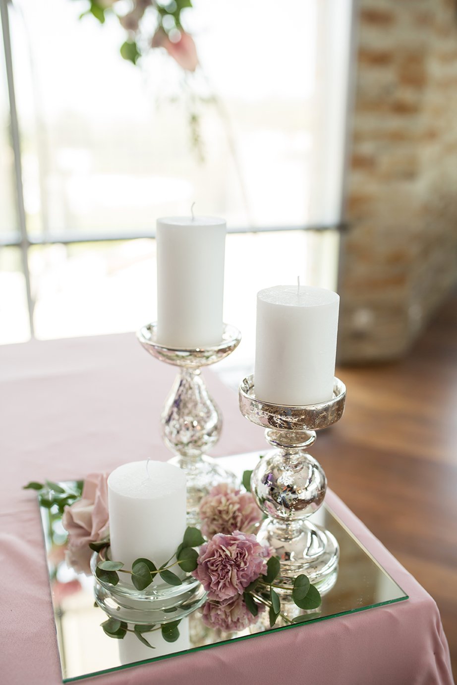 The wedding table setting for the newlyweds is decorated with fresh flowers of carnation, rose, anthurium and eucalyptus leaves. Silver candlesticks, white candles. Wedding floristry. Closeup details