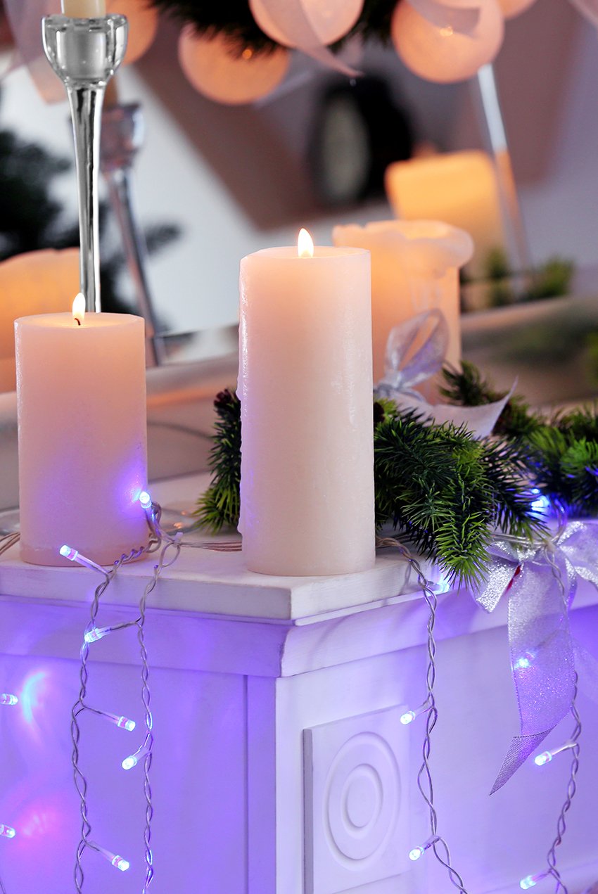 Candles on fireplace decorated for Christmas in living room