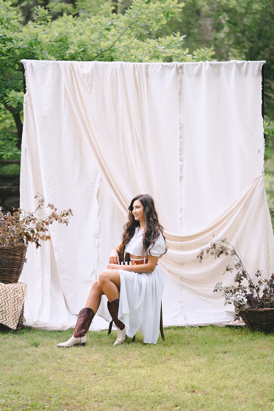 Pretty lady in long white dress with belt sitting and smiling in